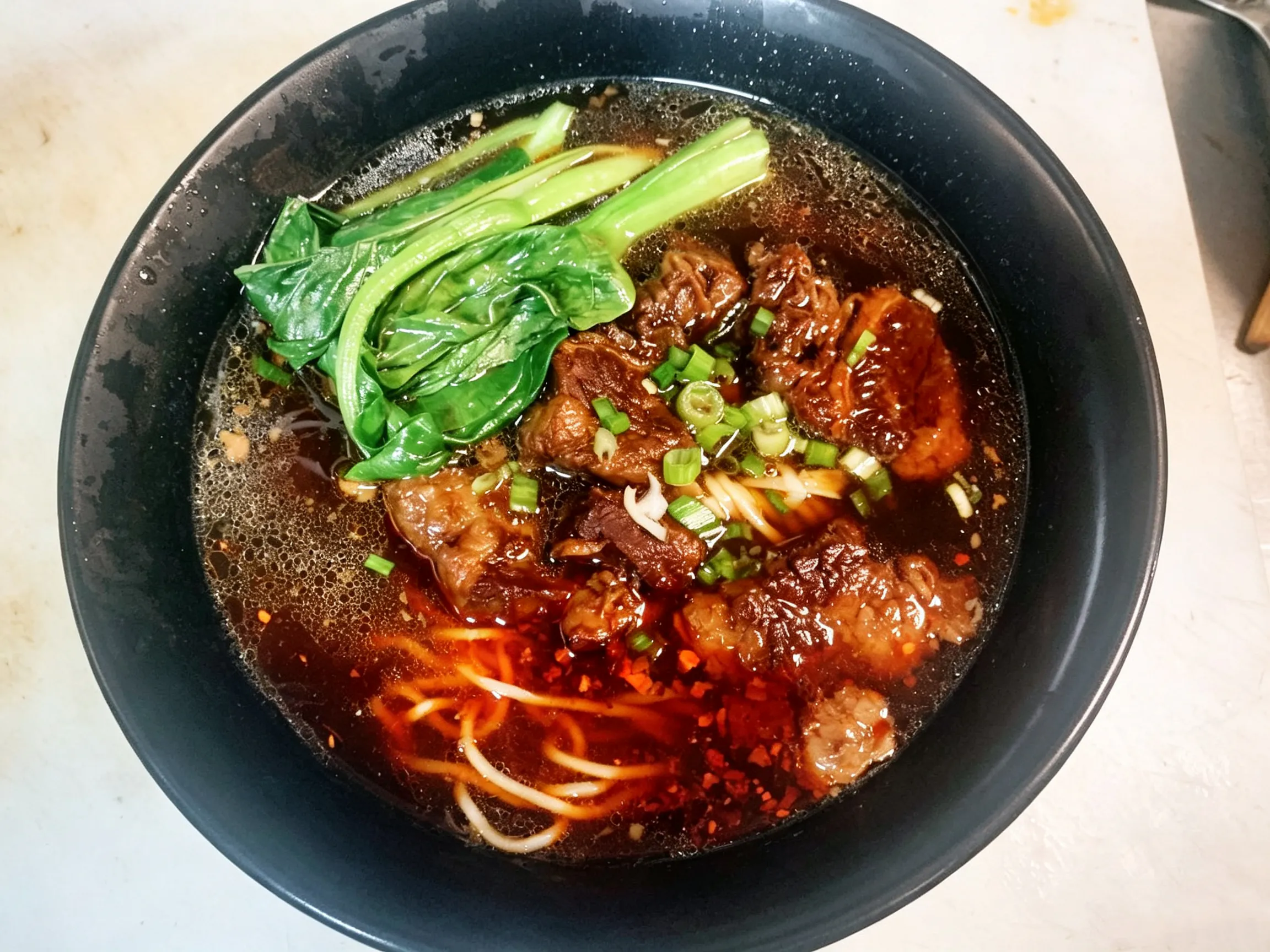 Braised beef noodle soup served with bok choy and chopped green onions at Yijia Kitchen，a Chinese Restaurant in Arcadia